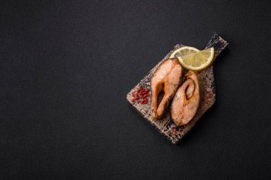 Lezzetli kırmızı somon balığı, çimento arka planda baharat ve otlarla kızartılmış.