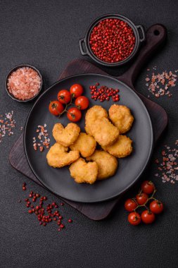 Delicious fresh crispy chicken nuggets on a dark concrete background. Unhealthy food, fast food