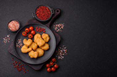 Delicious fresh crispy chicken nuggets on a dark concrete background. Unhealthy food, fast food