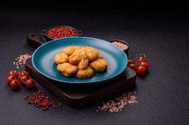 Delicious fresh crispy chicken nuggets on a dark concrete background. Unhealthy food, fast food