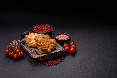 Lezzetli kızarmış domuz ya da koyu beton arka planda tuz ve baharatla ekilmiş tavuk pirzolası.