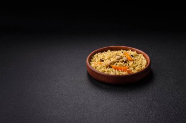 Lezzetli taze pilav, pirinç, havuç, et, soğan, baharat ve böğürtlen ile koyu beton arka planda seramik bir tabakta.