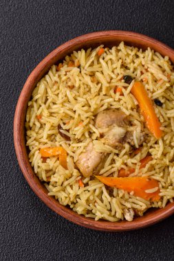 Lezzetli taze pilav, pirinç, havuç, et, soğan, baharat ve böğürtlen ile koyu beton arka planda seramik bir tabakta.