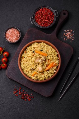 Lezzetli taze pilav, pirinç, havuç, et, soğan, baharat ve böğürtlen ile koyu beton arka planda seramik bir tabakta.