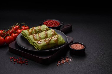 Koyu beton bir arka planda tavuk, mantar, tuz ve baharatla doldurulmuş ıspanaklı krep.