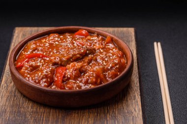 Tayland yemeği et, acı biber, domates sosu ve koyu beton arka planda susam.