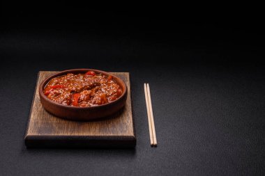 Tayland yemeği et, acı biber, domates sosu ve koyu beton arka planda susam.