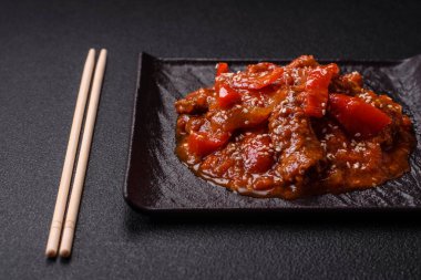 Tayland yemeği et, acı biber, domates sosu ve koyu beton arka planda susam.