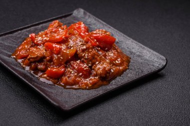 Tayland yemeği et, acı biber, domates sosu ve koyu beton arka planda susam.