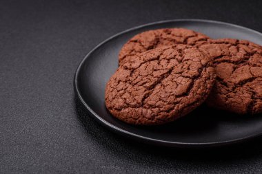 Lezzetli gevrek yulaf ezmeli kurabiyeler ve koyu beton arka planda çikolata.