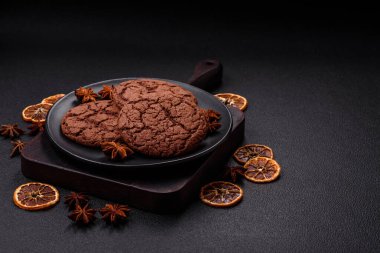 Lezzetli gevrek yulaf ezmeli kurabiyeler ve koyu beton arka planda çikolata.