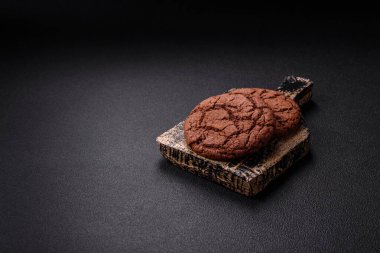 Lezzetli gevrek yulaf ezmeli kurabiyeler ve koyu beton arka planda çikolata.