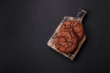 Lezzetli gevrek yulaf ezmeli kurabiyeler ve koyu beton arka planda çikolata.