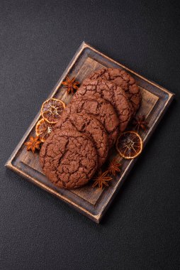 Lezzetli gevrek yulaf ezmeli kurabiyeler ve koyu beton arka planda çikolata.