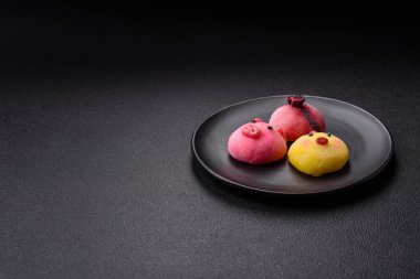 Renkli pirinç hamuru kabuğu ve koyu beton arka planda meyveli lezzetli Japon mochi tatlısı.