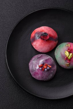 Renkli pirinç hamuru kabuğu ve koyu beton arka planda meyveli lezzetli Japon mochi tatlısı.