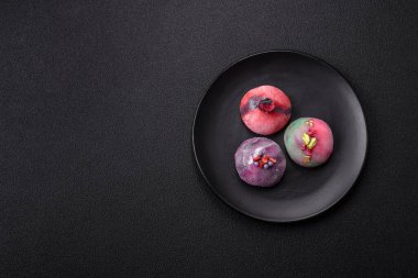 Renkli pirinç hamuru kabuğu ve koyu beton arka planda meyveli lezzetli Japon mochi tatlısı.