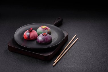 Renkli pirinç hamuru kabuğu ve koyu beton arka planda meyveli lezzetli Japon mochi tatlısı.