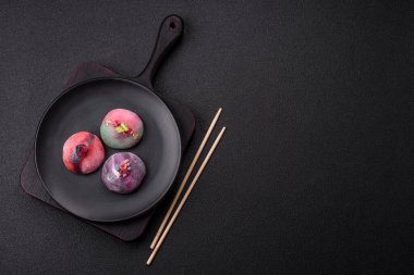 Renkli pirinç hamuru kabuğu ve koyu beton arka planda meyveli lezzetli Japon mochi tatlısı.