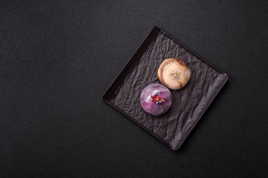 Renkli pirinç hamuru kabuğu ve koyu beton arka planda meyveli lezzetli Japon mochi tatlısı.