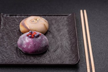 Renkli pirinç hamuru kabuğu ve koyu beton arka planda meyveli lezzetli Japon mochi tatlısı.