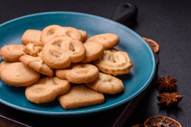Lezzetli taze, çıtır çıtır tereyağlı kurabiyeler seramik tabakta koyu beton arka planda.