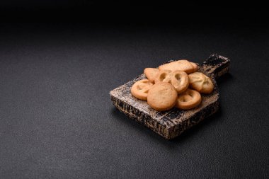 Lezzetli taze, çıtır çıtır tereyağlı kurabiyeler seramik tabakta koyu beton arka planda.