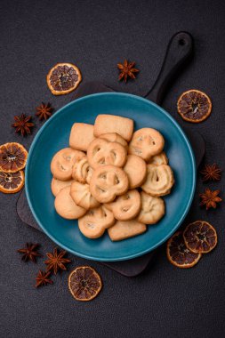Lezzetli taze, çıtır çıtır tereyağlı kurabiyeler seramik tabakta koyu beton arka planda.