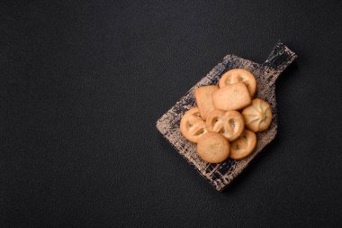 Lezzetli taze, çıtır çıtır tereyağlı kurabiyeler seramik tabakta koyu beton arka planda.
