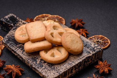Lezzetli taze, çıtır çıtır tereyağlı kurabiyeler seramik tabakta koyu beton arka planda.