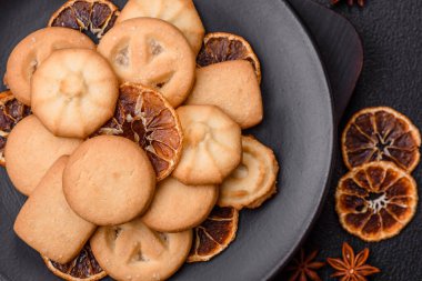 Lezzetli taze, çıtır çıtır tereyağlı kurabiyeler seramik tabakta koyu beton arka planda.