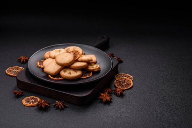 Lezzetli taze, çıtır çıtır tereyağlı kurabiyeler seramik tabakta koyu beton arka planda.