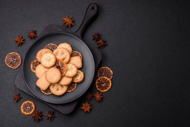 Lezzetli taze, çıtır çıtır tereyağlı kurabiyeler seramik tabakta koyu beton arka planda.