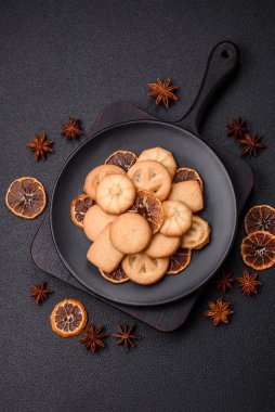 Lezzetli taze, çıtır çıtır tereyağlı kurabiyeler seramik tabakta koyu beton arka planda.