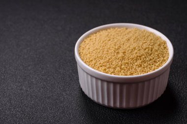 Koyu beton arka planda buğday lapası kuskus taneleri. Lezzetli, besleyici bir kahvaltı hazırlıyorum.