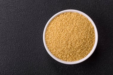 Koyu beton arka planda buğday lapası kuskus taneleri. Lezzetli, besleyici bir kahvaltı hazırlıyorum.