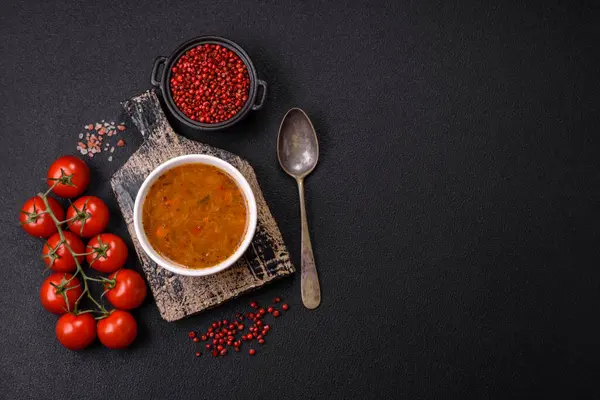 Sebzeli leziz sıcak domates çorbası, vejetaryen yemeği ve koyu betondan bir arka plan.