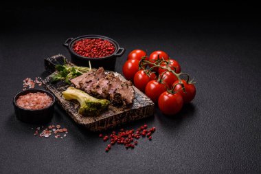 Fırında ton balığı, brokoli, domates ve fusili makarnalı, tuzlu ve baharatlı, koyu beton arka planda.