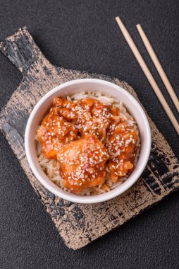 Asya yemekleri tatlı ve ekşi soslu haşlanmış pirinç, koyu beton arka planda baharatlar ve otlar.