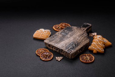 Boş ahşap kesme tahtası, fotokopi alanı, zencefilli kurabiyeler ve koyu desenli Noel dekoru.