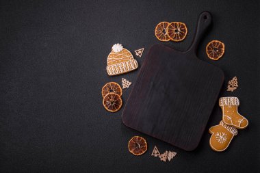 Boş ahşap kesme tahtası, fotokopi alanı, zencefilli kurabiyeler ve koyu desenli Noel dekoru.