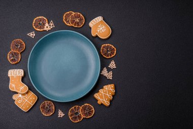 Siyah desenli arka planda zencefilli kurabiye ve Noel elementleriyle dolu boş seramik fotokopi alanı tabağı