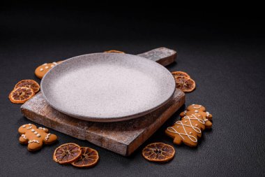 Siyah desenli arka planda zencefilli kurabiye ve Noel elementleriyle dolu boş seramik fotokopi alanı tabağı