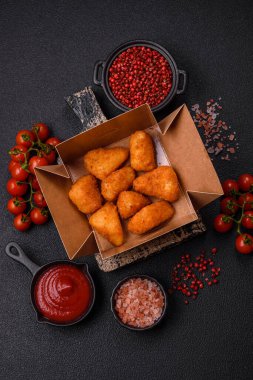 Koyu beton bir arka planda tuzlu ve baharatlı nugget şeklinde pişirilmiş peynirli krema ya da peynirli sandviç.