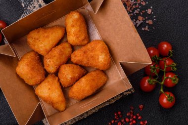 Koyu beton bir arka planda tuzlu ve baharatlı nugget şeklinde pişirilmiş peynirli krema ya da peynirli sandviç.