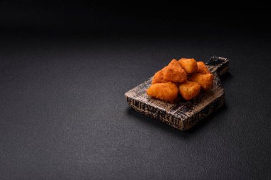 Koyu beton bir arka planda tuzlu ve baharatlı nugget şeklinde pişirilmiş peynirli krema ya da peynirli sandviç.