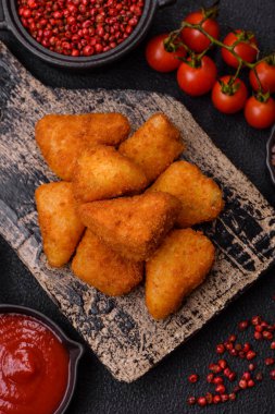 Koyu beton bir arka planda tuzlu ve baharatlı nugget şeklinde pişirilmiş peynirli krema ya da peynirli sandviç.