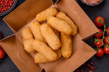 Fast food peynirli çubuklar, koyu beton arka planda tuz ve baharatlar.