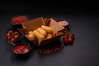 Fast food peynirli çubuklar, koyu beton arka planda tuz ve baharatlar.