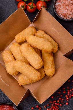 Fast food peynirli çubuklar, koyu beton arka planda tuz ve baharatlar.